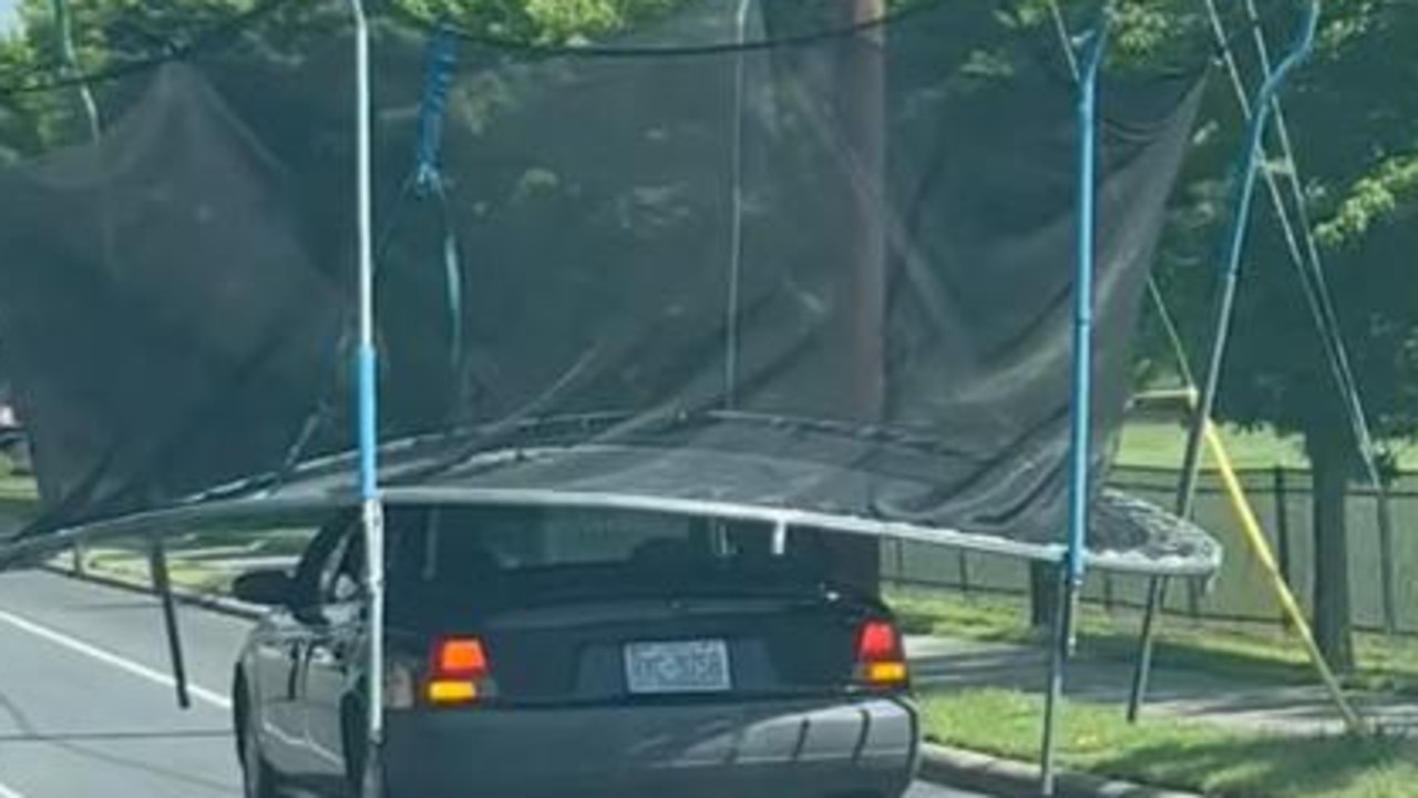 Car filmed driving trampoline on roof down main road